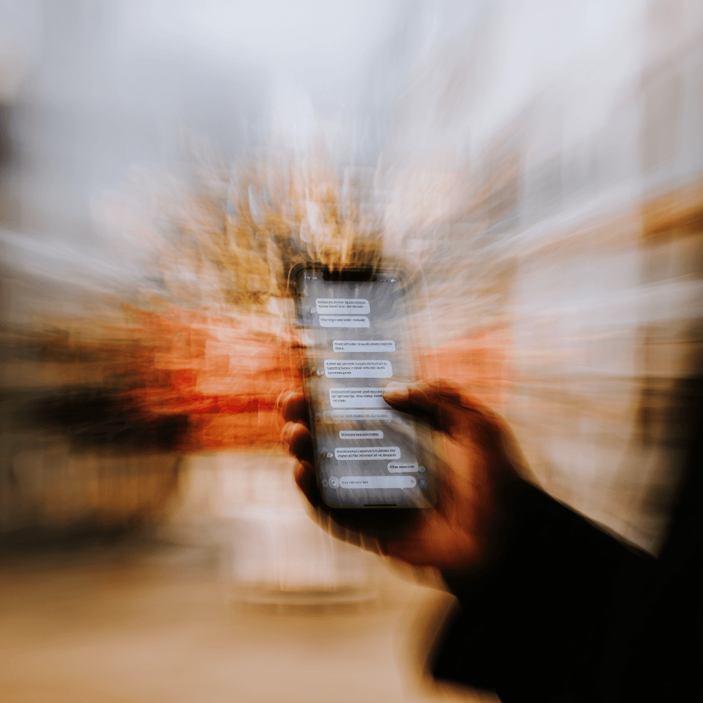 Motion-blurred hand holding a phone with a messaging app, conveying real human conversation data.