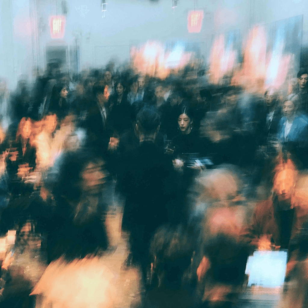 A motion-blurred crowd of professionals moving through a brightly lit interior.